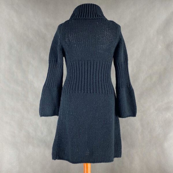 Czarny długi sweter damski. Sweter jest zrobiony z miłego w dotyku materiału, który składa się w 50% z wełny i w 50% z akrylu. Sweter można traktować jako narzutkę, nie ma zapięć. Dekolt w trójkąt, długie rękawy. W okolicach talii nieco zwężany, dzięki czemu ładnie podkreśla sylwetkę.