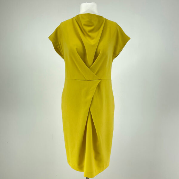 Żółta sukienka z krótkim rękawem. Zapinana z tyłu na suwak. Z przodu pod szyją luźno opadający materiał. Sięga mniej więcej do kolan.
